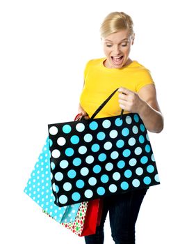Young girl looking excitedly inside her shopping bag, completely thrilled