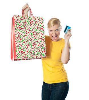Shopaholic teenager posing in excitement. Holding paper bag and card