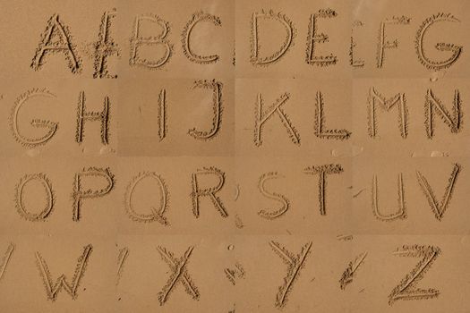 The alphabet written in sand on a beach.