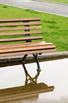 A bench and reflection in the park after the rain