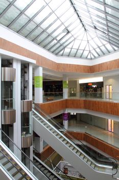 Hall with columns and escalators in huge shopping center. A view from the top floor on escalators and lifts