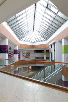 Hall with columns and escalators in huge shopping center. A view of the glazed ceiling