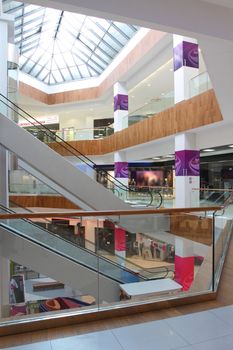 Hall with columns and escalators in huge shopping center. A view of ladders between floors