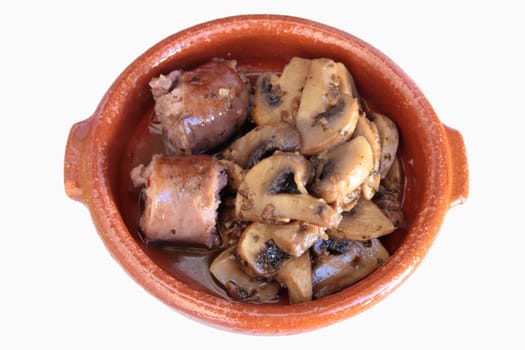 clay plate full of sausages with mushrooms Spanish sauce on white background