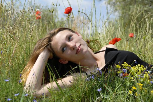 young girl laid down in a field with flowers