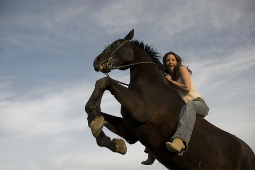 happy girl and rearing stallion in blue sky