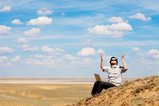 man with laptop praying to the God outdoors