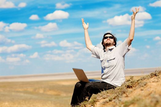 man with laptop praying to the God outdoors
