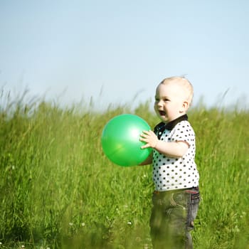  little boy play in green grass with green ball