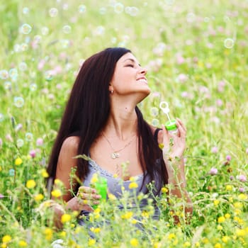  happy woman smile in green grass soap bubbles around