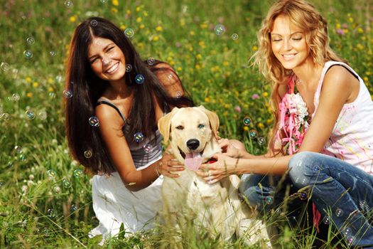girlfriends and dog in green grass field