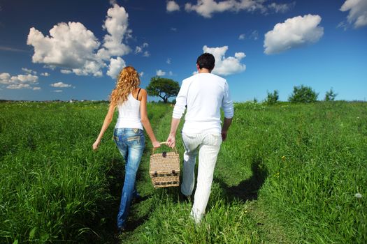 man and woman walk on picnic in green grass