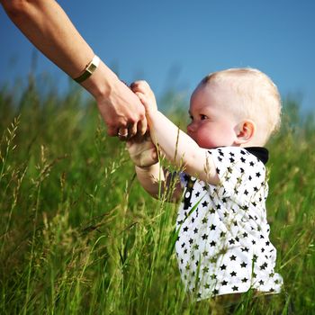 boy and mother hands in grass field