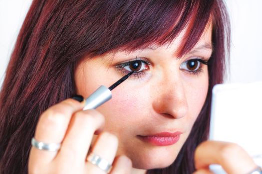 Young beautiful woman applying eyeliner on eyelid - isolated on white background