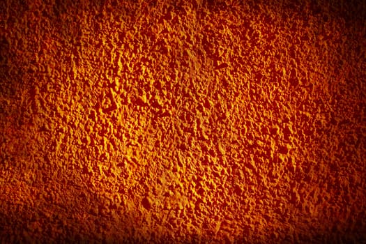 Orange painted wall with small stones textured in a grunge style for background.