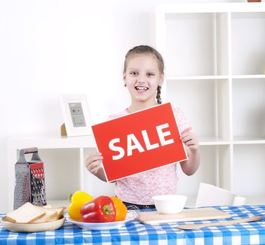 Young child cooking fresh meal at home and holding sale sign