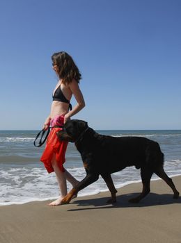 woman and big purebred rottweiler on the beach