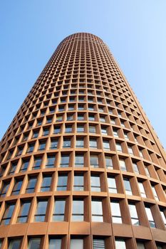 Architecture: perspective shot of a modern circular high rise tower with sky.