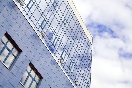 windows of skyscraper with reflections on a background cloudy sky