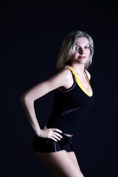 Beautiful, sexy woman athlete posing on a black background