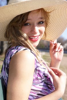 A young woman sits in the sunshine near the river.