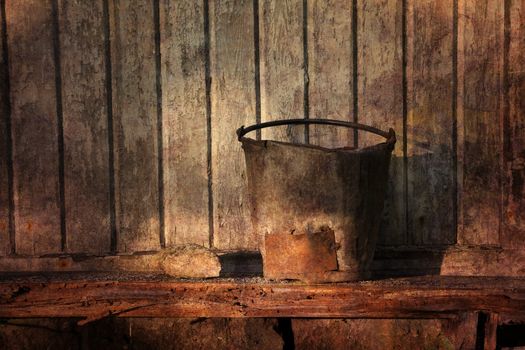 A rusty bucket in evening light textured in a grungy style.