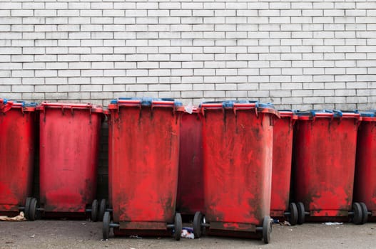 many red dirty garbage bins against a gray brick wall (copy-space available)    