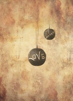 Two slate balls with the message love and compassion written by hand in chalk hanging freely, in grunge style.