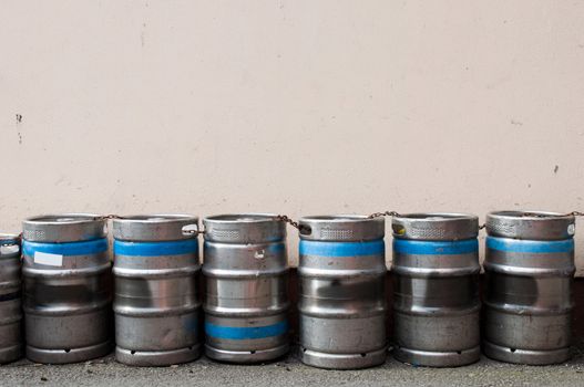 row of beer kegs against a light pink wall (copy-space available)