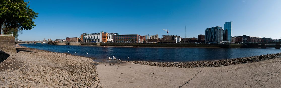 stunning Limerick cityscape panorama from Shannon bridge to Sarsfield Bridge, featuring Riverpoint buildings and river Shannon with swans (gorgeous blue sky)