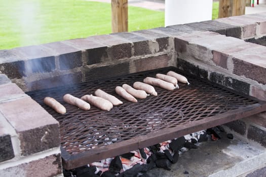 Brick barbeque with sausages cooking on grill