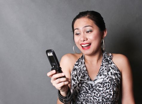 A very happy young woman looking at her cellphone.