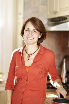 Smiling mature woman enjoying cooking in kitchen at home