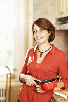 Smiling mature woman enjoying cooking in kitchen at home