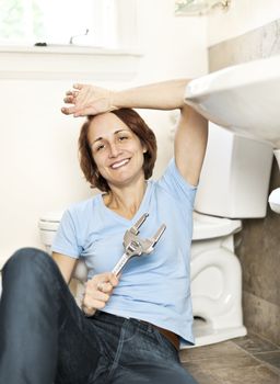 Woman repairing sink in bathroom at home