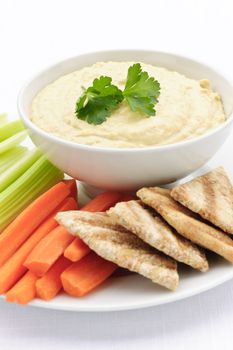 Healthy snack of hummus dip with pita bread slices and vegetables