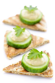 Appetizer of hummus and cucumber slices on pita bread