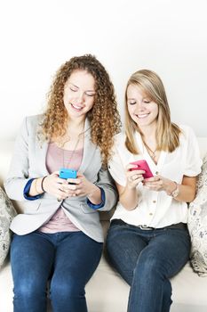 Two smiling women using mobile devices with colorful cases