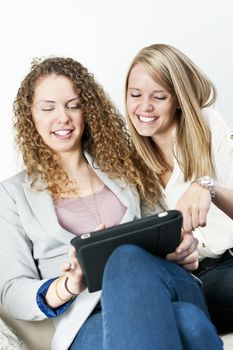 Two young smiling women using tablet computer at home