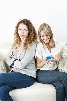 Young woman ignoring her friend checking smart phone breaching cellphone etiquette