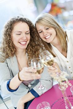 Two happy women celebrating with glasses of white wine