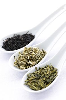 Black, white and green dry tea leaves in spoons