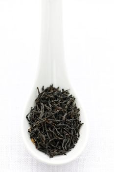 Black dry tea leaves on a spoon