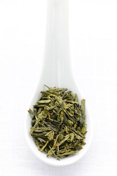 Green dry tea leaves on a spoon