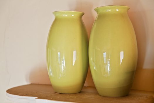 Two olive green vases on a cottage shelf, part of a set