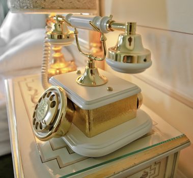Interior room design with ornate ceramic dog and bone style retro telephone on bedside table with lamp