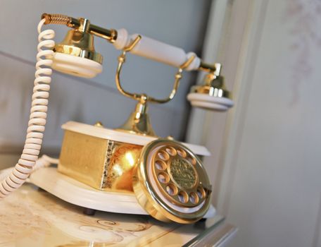 Interior design element of gold and brass ceramic telephone retro style on a bedside table