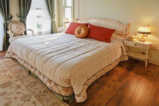 Horizontal shot of luxurious bedroom, fine appointed detail with white bedrobes and ornate bedside table