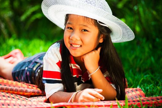 Young girl lying on a meadow with a hat on her head