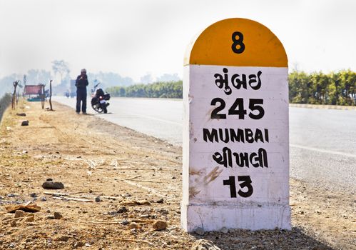 Gujarat India, morning sun, Milestone on Mumbai to Ahmedabad Road, the city still 245 kilometres